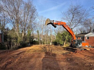Excavator clearing and grading land near residential homes