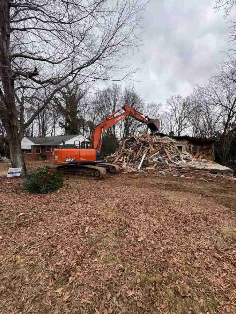 Excavator demolishing a house and piling up debris on site