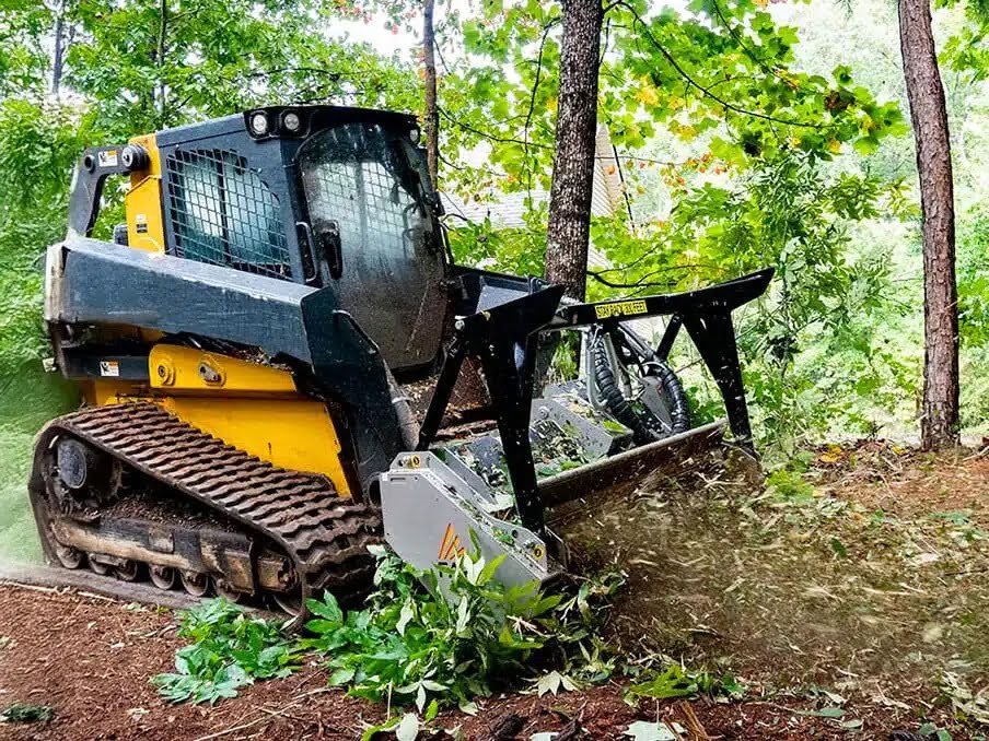 Land clearing machine removing brush and vegetation on a wooded lot