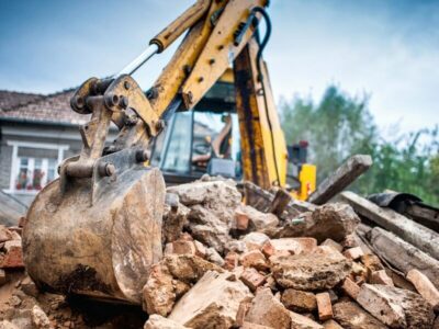 Excavator working through debris during a residential house demolition project