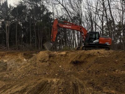 Excavator working on an active excavation site with exposed soil