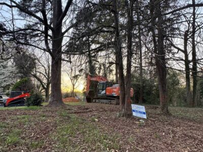 Excavator and skid steer clearing trees and brush on a wooded residential lot in the Charlotte area