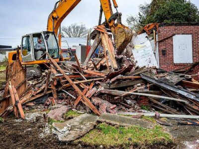 Excavator sorting wood, brick, and debris during a house demolition project