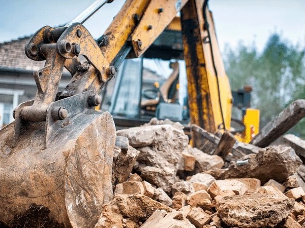 Excavator clearing debris from an old structure before property sale