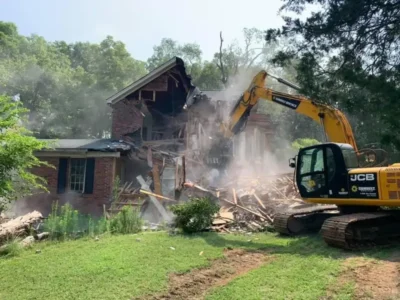 Excavator tearing down an older brick home during a residential demolition project in Charlotte