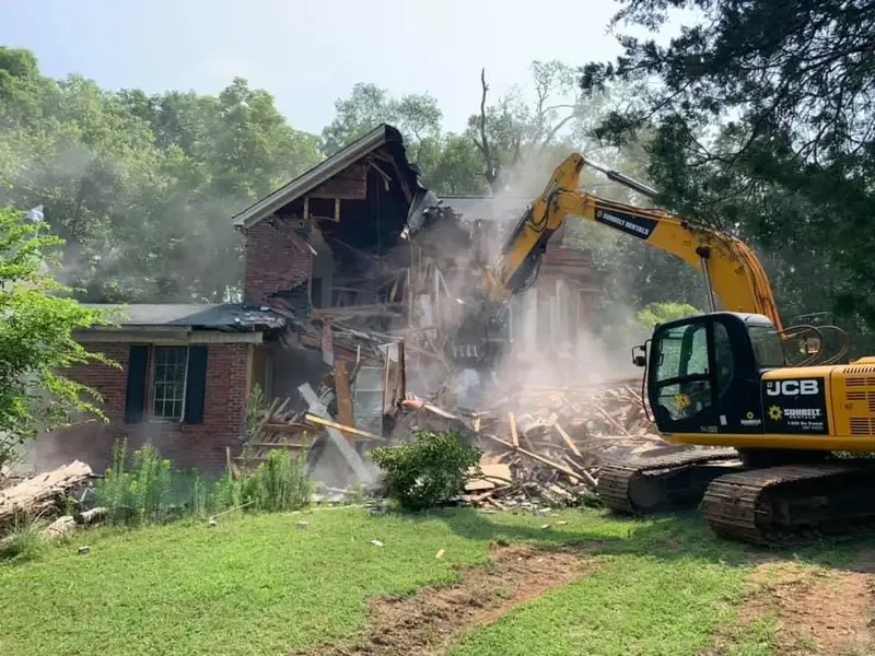 Excavator tearing down an older brick home during a residential demolition project in Charlotte