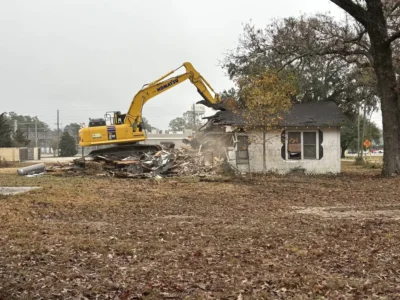 Excavator tearing down an older house during a residential demolition project