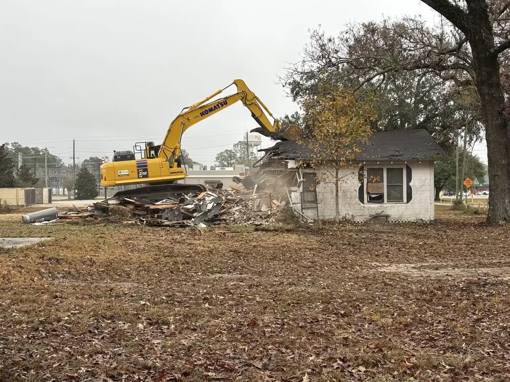 Excavator tearing down an older house during a residential demolition project