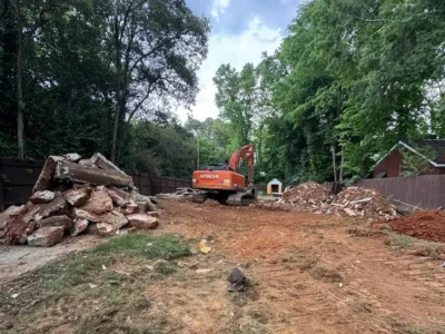 Excavator clearing concrete and demolition debris from a residential lot